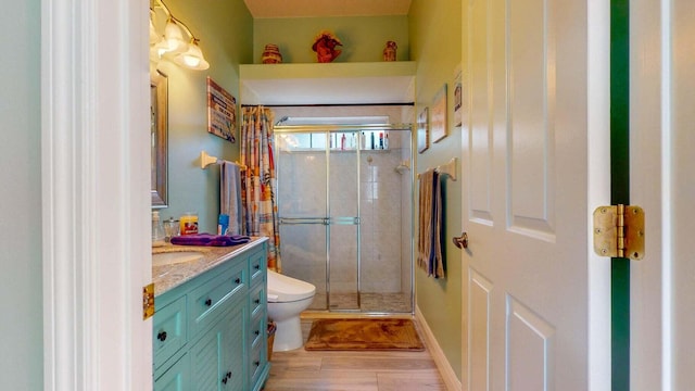 bathroom featuring walk in shower, hardwood / wood-style floors, vanity, and toilet