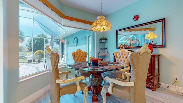 dining room with hardwood / wood-style floors, a healthy amount of sunlight, and an inviting chandelier