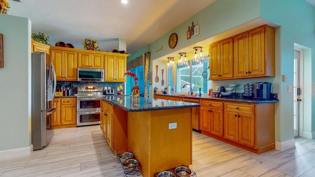 kitchen featuring sink, tasteful backsplash, light hardwood / wood-style floors, a kitchen island, and appliances with stainless steel finishes