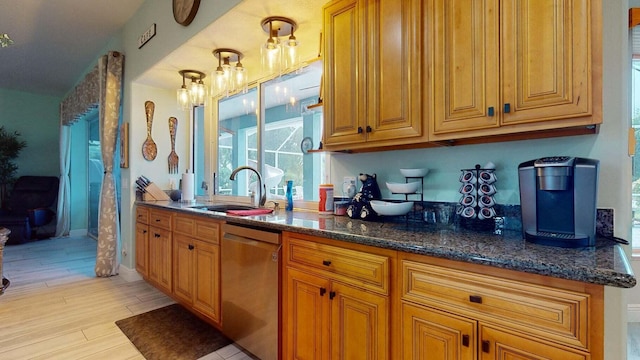 kitchen with stainless steel dishwasher, sink, pendant lighting, dark stone countertops, and light hardwood / wood-style floors