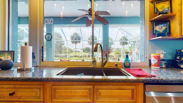 kitchen featuring ceiling fan, dark stone countertops, sink, and dishwasher