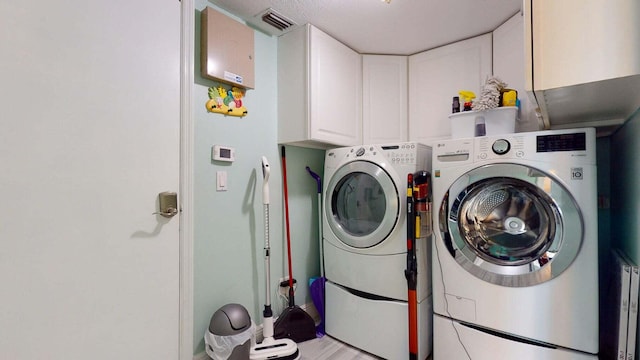 clothes washing area with cabinets and separate washer and dryer