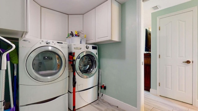 clothes washing area with cabinets and washer and clothes dryer