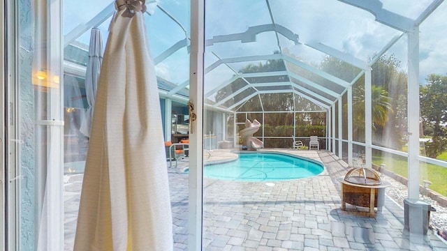 view of swimming pool featuring glass enclosure, a patio, and a fire pit