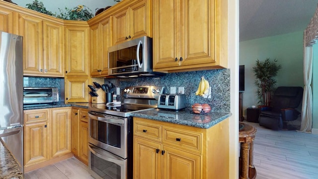 kitchen featuring backsplash, dark stone countertops, light hardwood / wood-style flooring, and stainless steel appliances