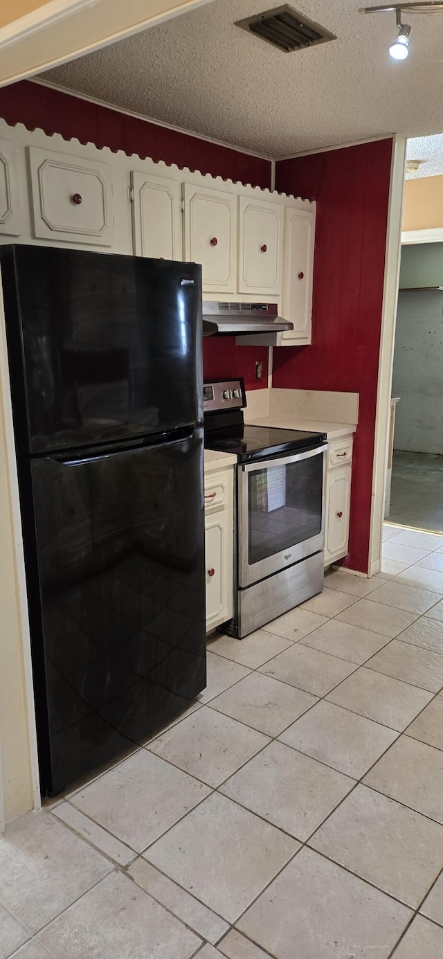 kitchen featuring white cabinets, black refrigerator, stainless steel electric range oven, a textured ceiling, and light tile patterned floors