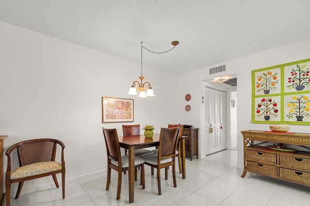 dining area with a textured ceiling, an inviting chandelier, and light tile patterned flooring