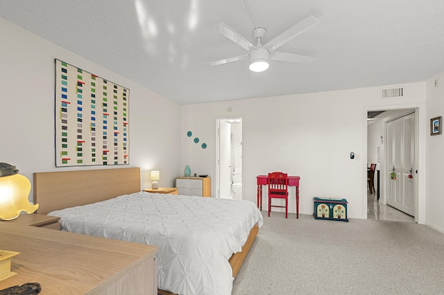 carpeted bedroom featuring ensuite bath, ceiling fan, and a textured ceiling