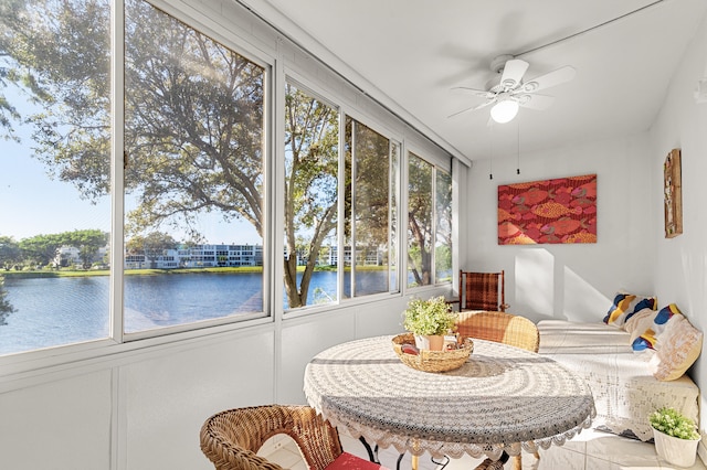 sunroom featuring ceiling fan and a water view