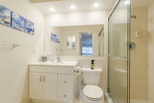 bathroom featuring walk in shower, vanity, tile walls, and toilet