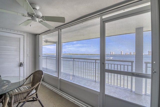 sunroom featuring ceiling fan and a water view