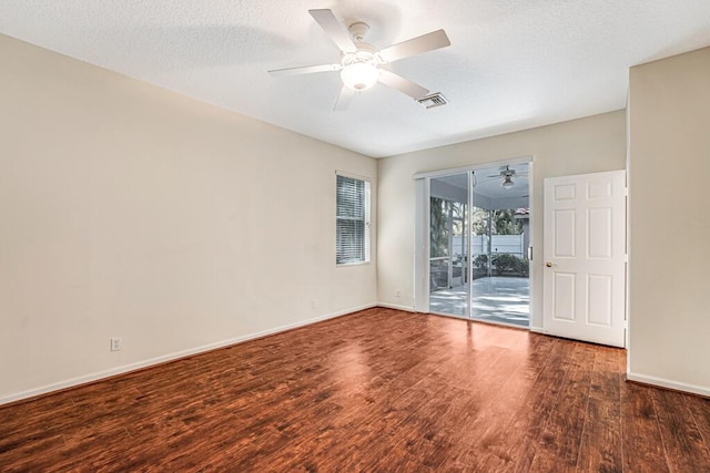 spare room with a textured ceiling, ceiling fan, and dark wood-type flooring