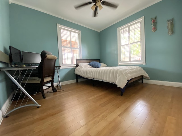 bedroom featuring multiple windows, light wood-type flooring, ceiling fan, and crown molding