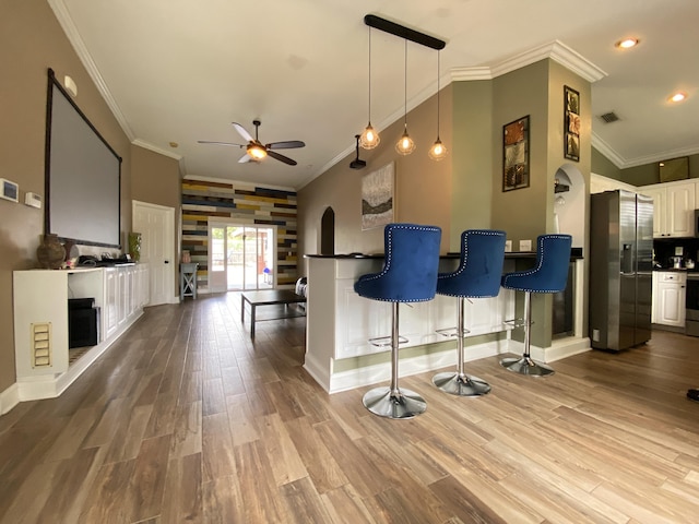 kitchen with white cabinetry, ceiling fan, stainless steel refrigerator with ice dispenser, crown molding, and wood-type flooring