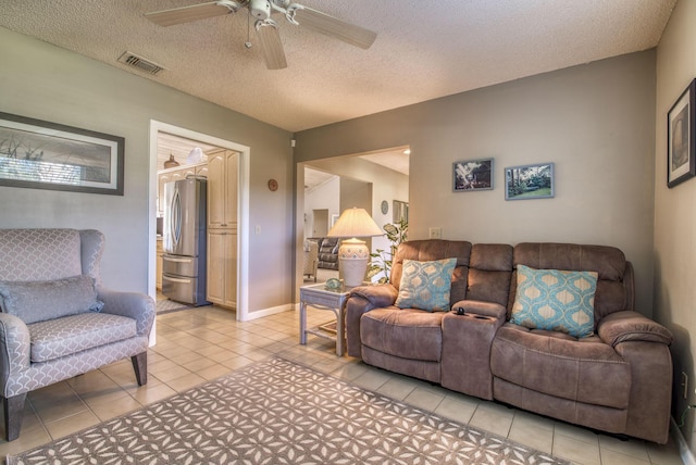 living room featuring ceiling fan, light tile patterned flooring, and a textured ceiling