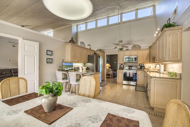 dining area with a high ceiling, ceiling fan, and light tile patterned flooring
