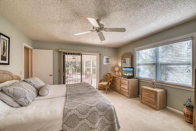 bedroom featuring access to exterior, multiple windows, light colored carpet, a ceiling fan, and a textured ceiling