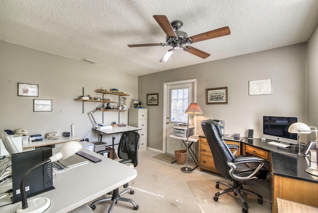 office area with ceiling fan, a textured ceiling, light colored carpet, and baseboards