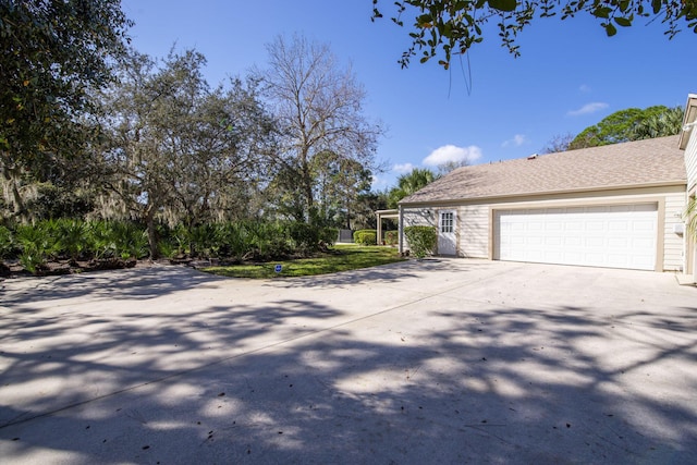view of front of home featuring concrete driveway, an attached garage, and a shingled roof