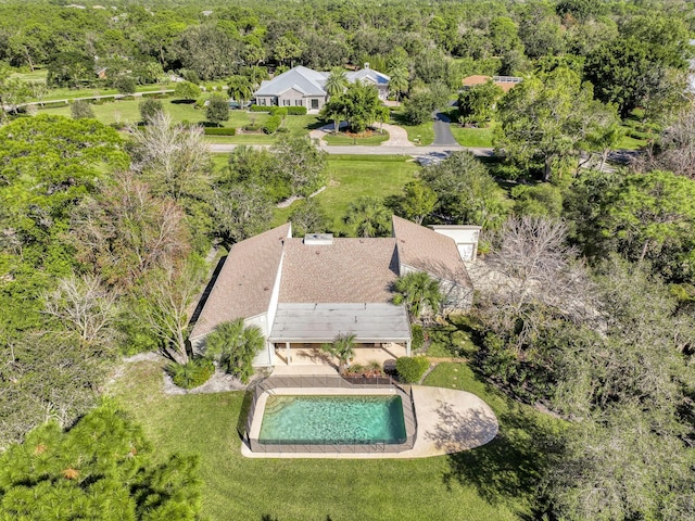 view from above of property featuring a pool and a heavily wooded area