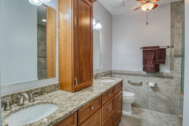 bathroom featuring ceiling fan, toilet, tile walls, and vanity