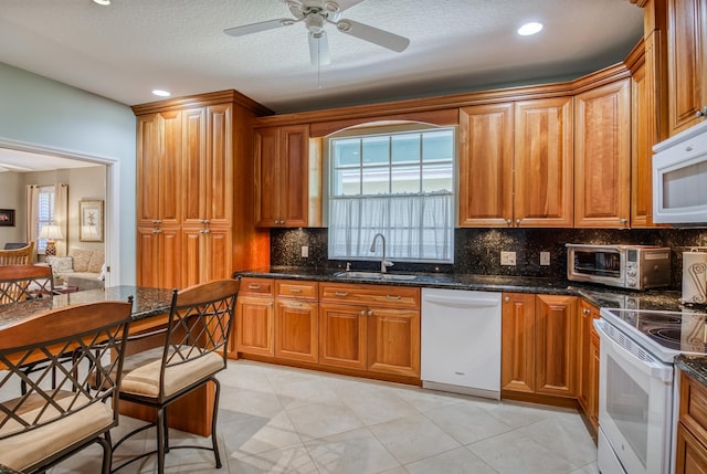 kitchen featuring white appliances, sink, dark stone countertops, light tile patterned floors, and tasteful backsplash