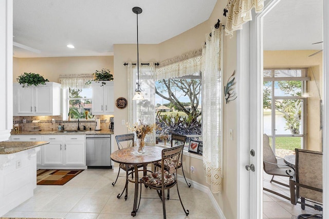 kitchen with dishwasher, sink, a healthy amount of sunlight, pendant lighting, and white cabinets