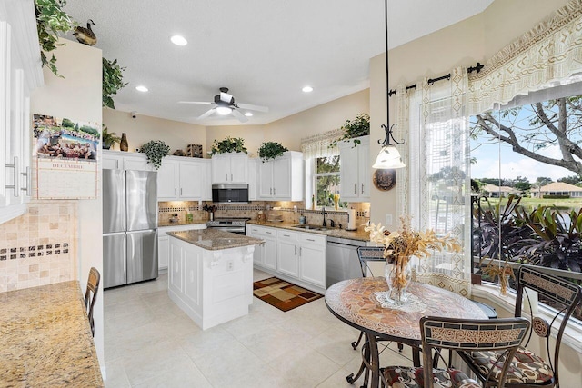 kitchen featuring sink, hanging light fixtures, appliances with stainless steel finishes, tasteful backsplash, and a kitchen island