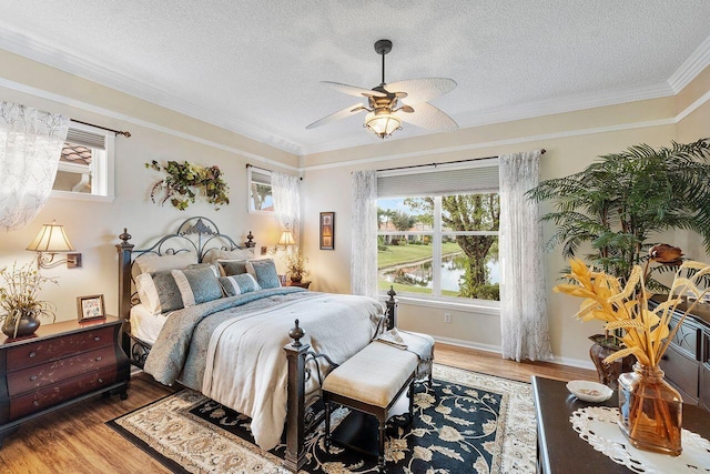 bedroom featuring a textured ceiling, ceiling fan, wood-type flooring, and crown molding