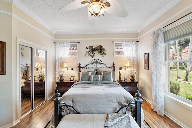 bedroom with ceiling fan, light hardwood / wood-style flooring, crown molding, a textured ceiling, and a closet