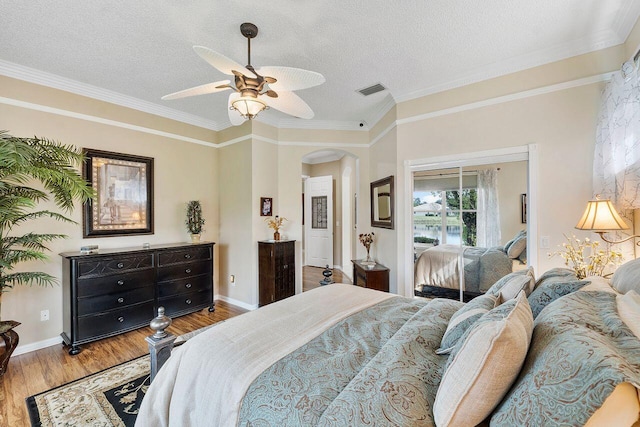 bedroom featuring ceiling fan, ornamental molding, a textured ceiling, and light wood-type flooring