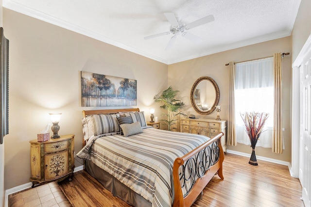 bedroom with a textured ceiling, light hardwood / wood-style flooring, ceiling fan, and ornamental molding