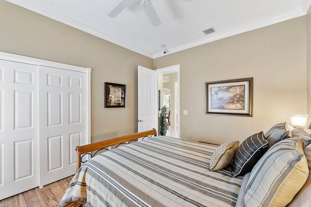 bedroom featuring light wood-type flooring, a closet, crown molding, and ceiling fan