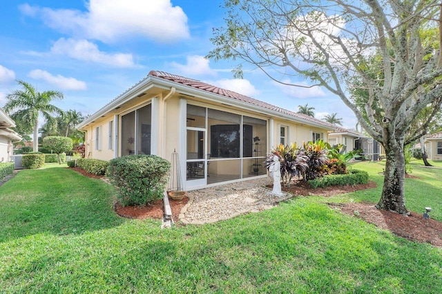 back of property with a yard and a sunroom