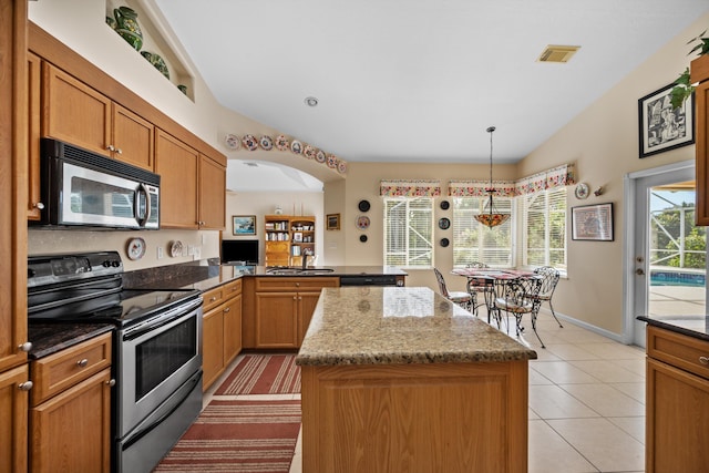 kitchen featuring appliances with stainless steel finishes, a center island, decorative light fixtures, kitchen peninsula, and stone counters