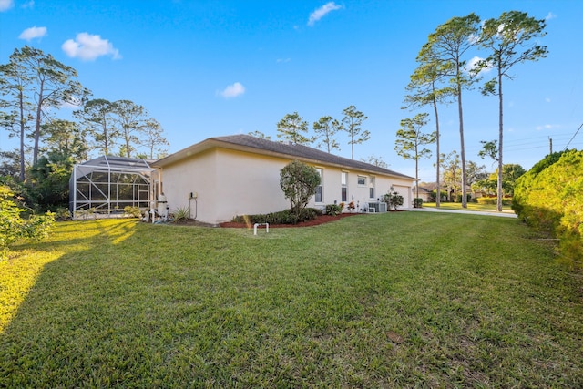 rear view of property featuring glass enclosure, a yard, a garage, and central AC unit