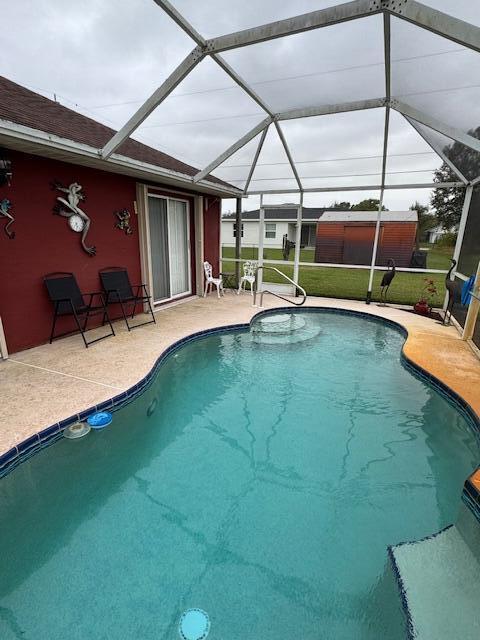 view of pool with glass enclosure and a patio area