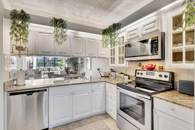 kitchen featuring light stone counters, stainless steel appliances, sink, light tile patterned floors, and white cabinets