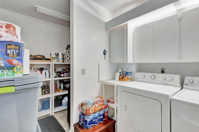 washroom with cabinets, a textured ceiling, and washer and clothes dryer