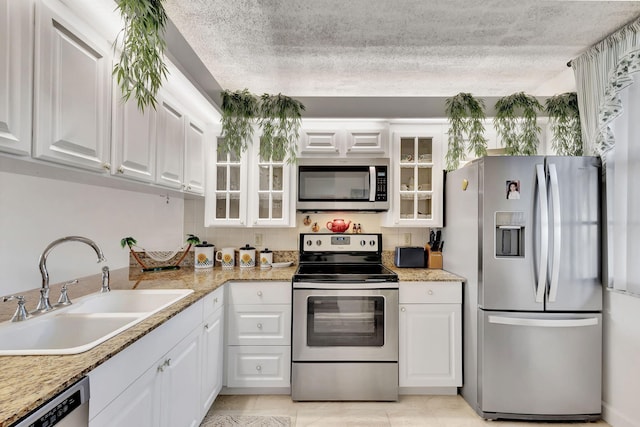 kitchen with light tile patterned floors, stainless steel appliances, white cabinetry, and sink