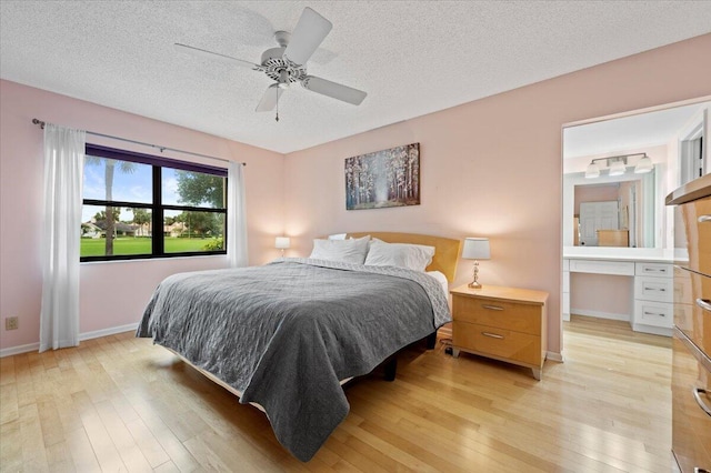 bedroom featuring ceiling fan, built in desk, light hardwood / wood-style floors, and a textured ceiling