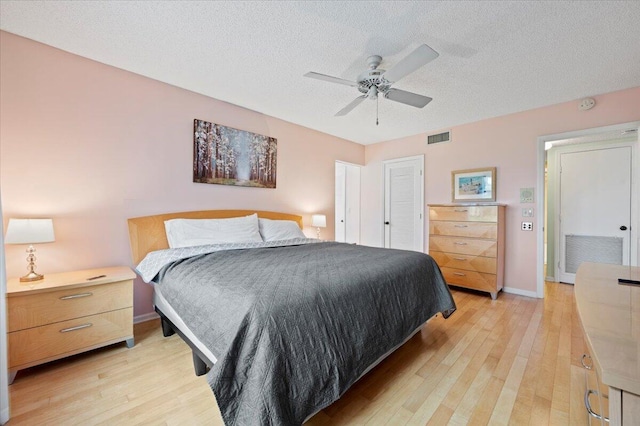 bedroom with ceiling fan, light hardwood / wood-style flooring, and a textured ceiling