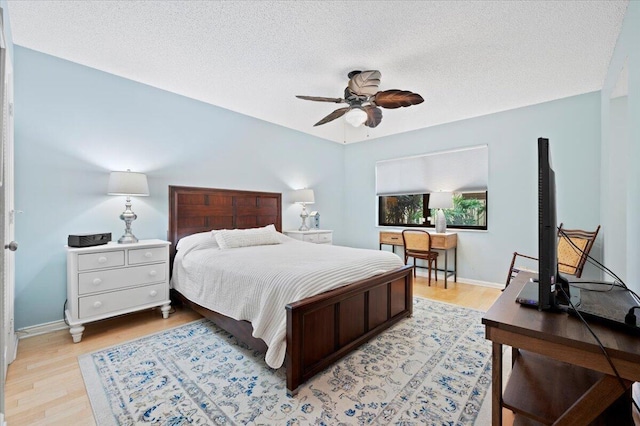 bedroom with a textured ceiling, light hardwood / wood-style floors, and ceiling fan