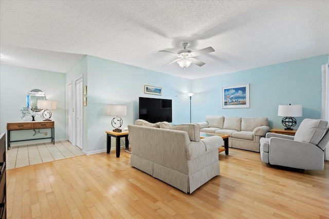 living room featuring a textured ceiling, light wood-type flooring, and ceiling fan