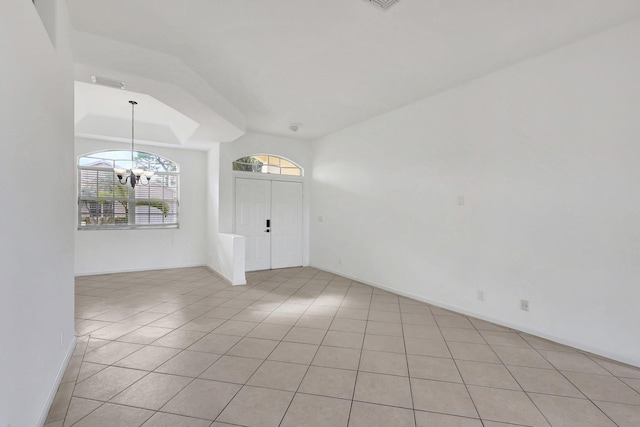 tiled empty room featuring an inviting chandelier