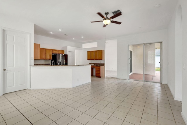 kitchen with kitchen peninsula, ceiling fan, light tile patterned floors, stone counters, and stainless steel fridge with ice dispenser