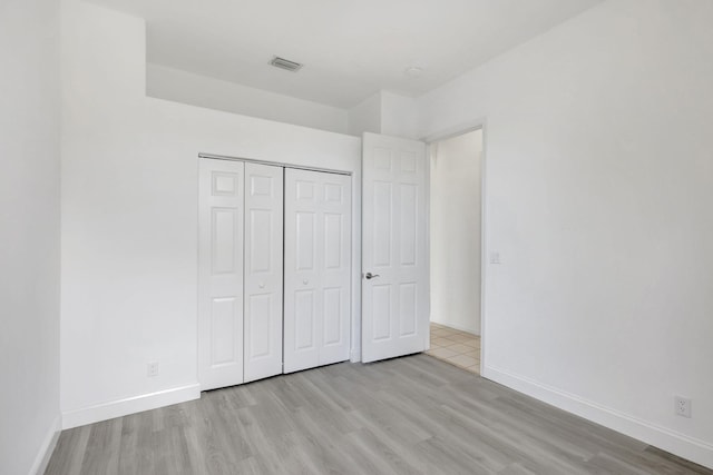 unfurnished bedroom with light wood-type flooring and a closet