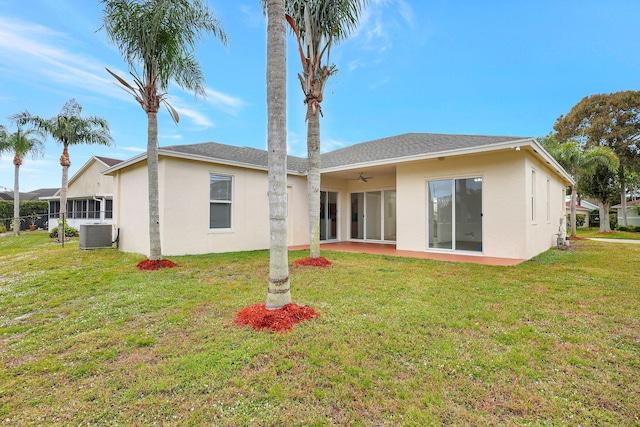 rear view of property with central air condition unit, ceiling fan, and a yard