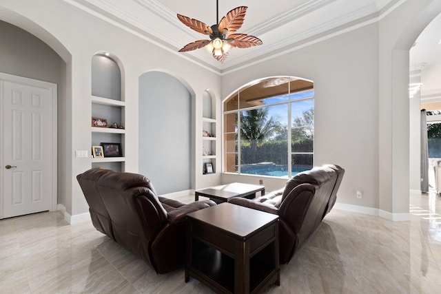 living room featuring built in shelves, ceiling fan, and crown molding