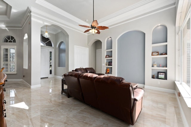 living room with built in shelves, ceiling fan, and crown molding